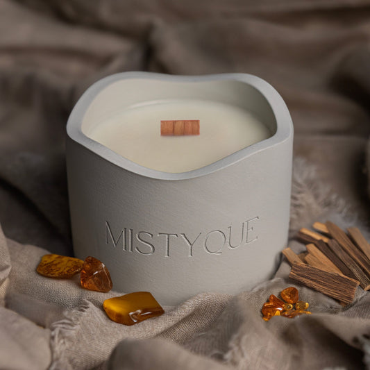 Mistyque candle in light grey concrete pot with wooden wick, styled with amber stones and cinnamon — Golden Hour standard candle