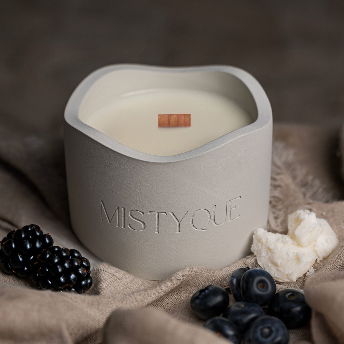 Noir Berry Fusion in a light grey concrete pot with wooden wick, styled with blueberries and a piece of wax - Noir Berry Fusion standard candle